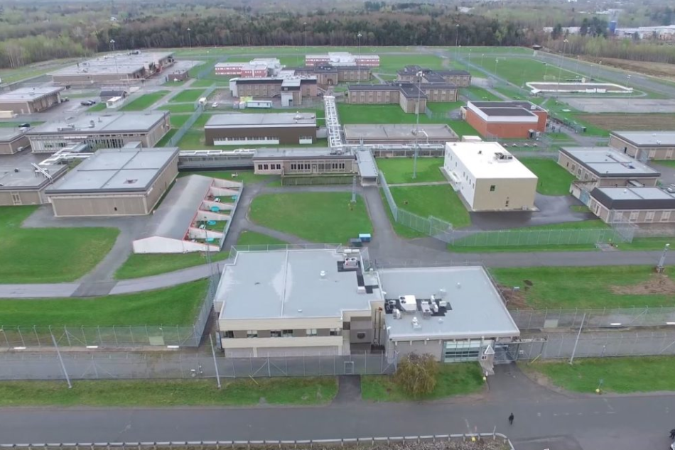 Vue aérienne du complexe carcéral de Donnacona, montrant les bâtiments sécurisés, les clôtures périmétriques et les installations extérieures sur un vaste terrain verdoyant