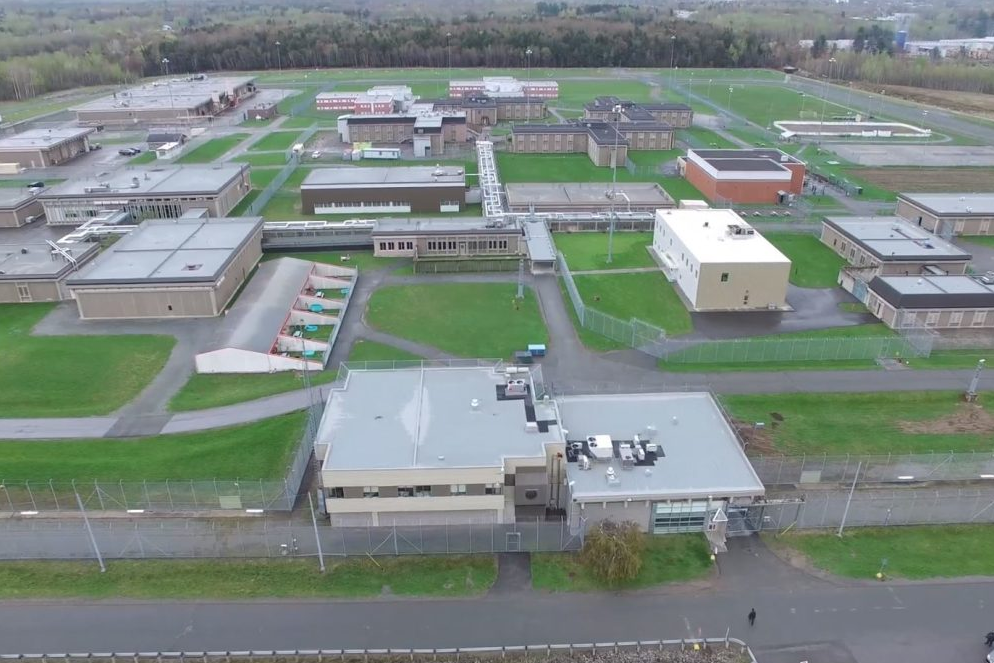 Vue aérienne du complexe carcéral de Donnacona, montrant les bâtiments sécurisés, les clôtures périmétriques et les installations extérieures sur un vaste terrain verdoyant